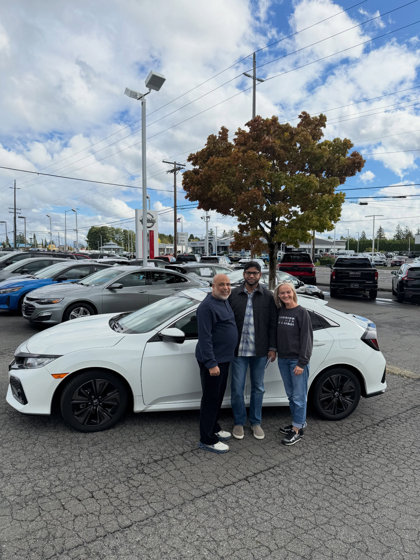 Joli and the Civic’s family standing beside their white 2019 Honda Civic at Nissan of Everett