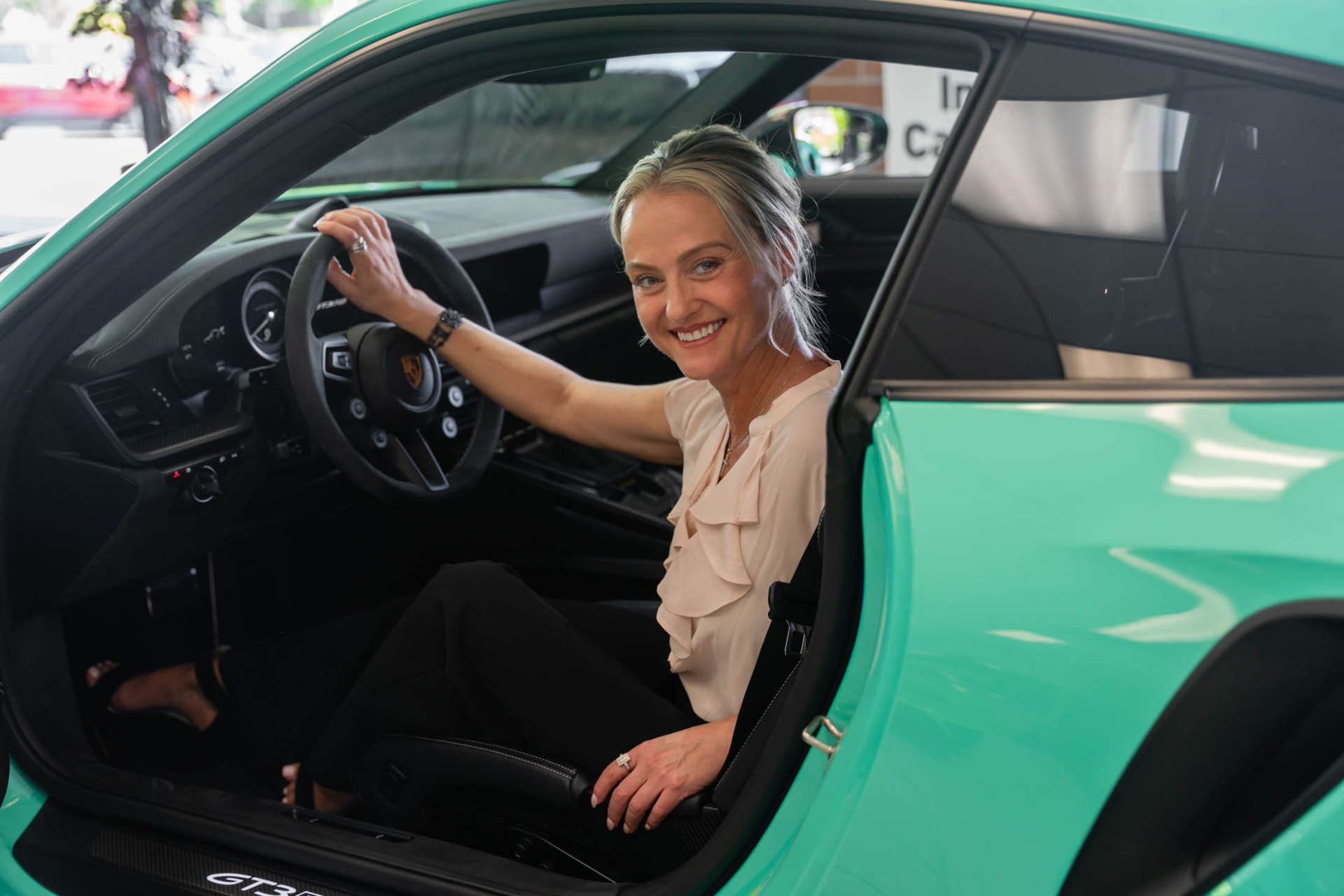 Joli smiling from the driver's seat of a sports car