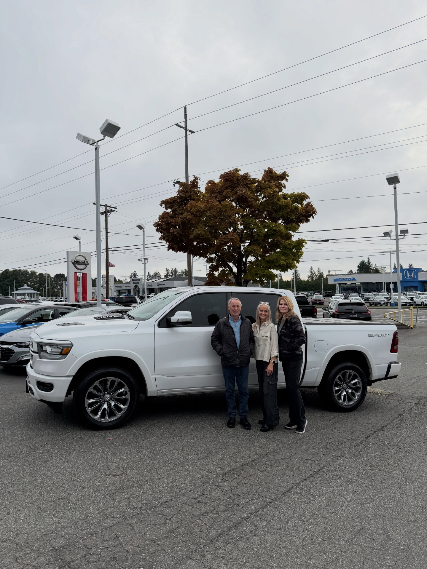 Joli standing with Brenda and Warren beside their white 2020 Ram 1500 at Nissan of Everett