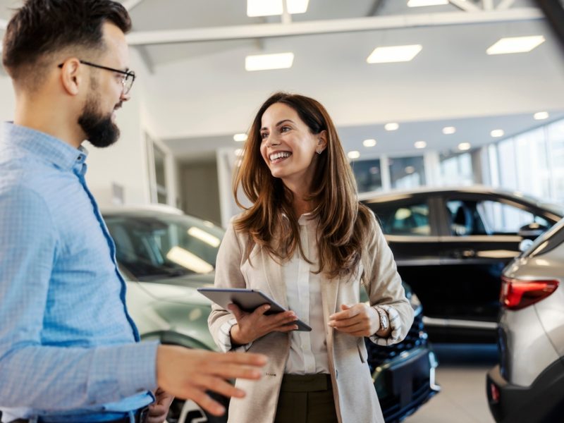 Friendly,Female,Car,Dealer,Standing,At,Fancy,Car,Showroom,And Friendly,Female,Car,Dealer,Standing,At,Fancy,Car,Showroom,And